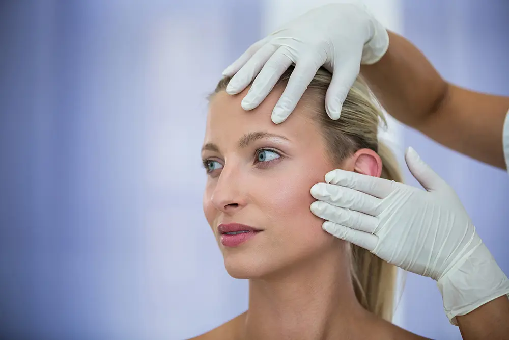 Examining a woman's face for cosmetic treatment