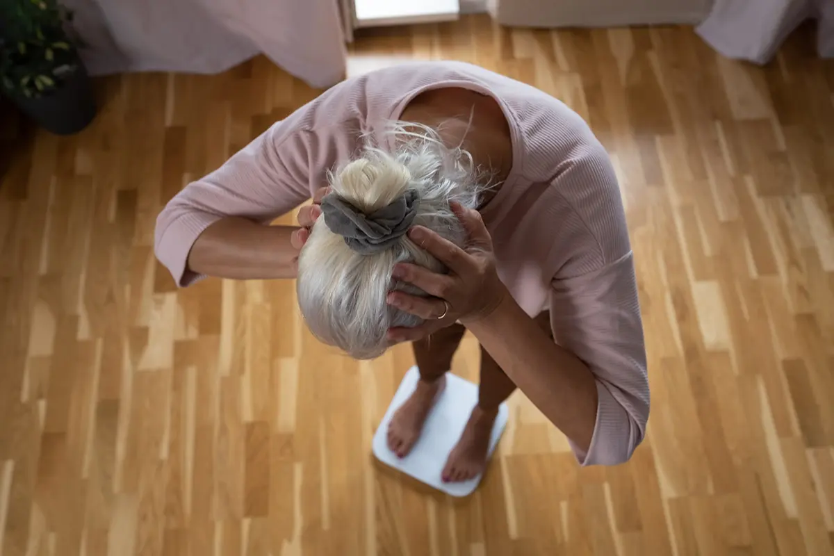 Woman stepping floor scales closeup weight control